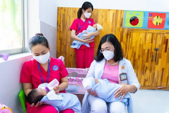 PGS.TS.BS Hoàng Thị Diễm Tuyết (áo trắng) - Giám đốc Bệnh viện Hùng Vương - cùng các nhân viên chăm sóc những em bé sinh trong tâm dịch COVID-19, ảnh BVCC
