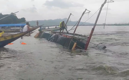 Một người đứng trên phần còn lại của con thuyền bị lật ở vùng biển ngoài khơi bờ biển Barangay Kalinawan, Binangonan, Rizal vào chiều ngày 27/7 - Ảnh: PCG