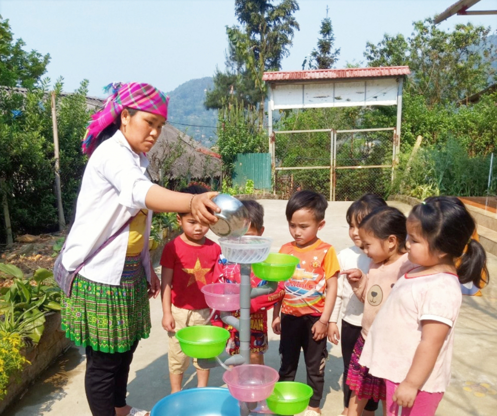 Một phụ huynh xã Cao Phạ, huyện Mù Cang Chải hướng dẫn thực hành cho các cháu mầm non - ẢNH: M.C.