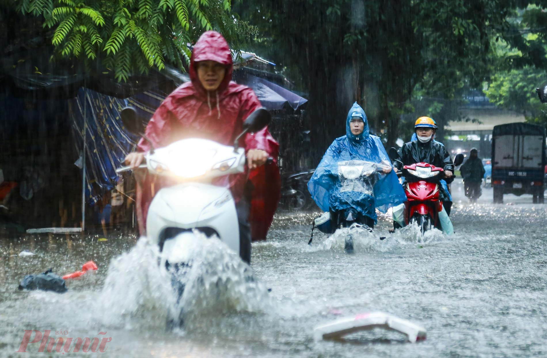 Ghi nhận tại phường Nhật Tảo (quận Bắc Từ Liêm, Hà Nội) Không ít người dân phải dầm mưa, bì bõm dắt xe qua đoạn đường ngập sâu. 