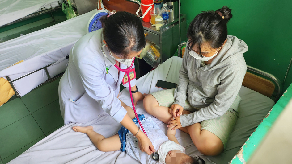 ác sĩ Trần Ngọc Lưu - Khoa Nhiễm Bệnh viện Nhi Đồng 2 - thăm khám cho bé mắc sốt xuất huyết - Ảnh: Phạm An