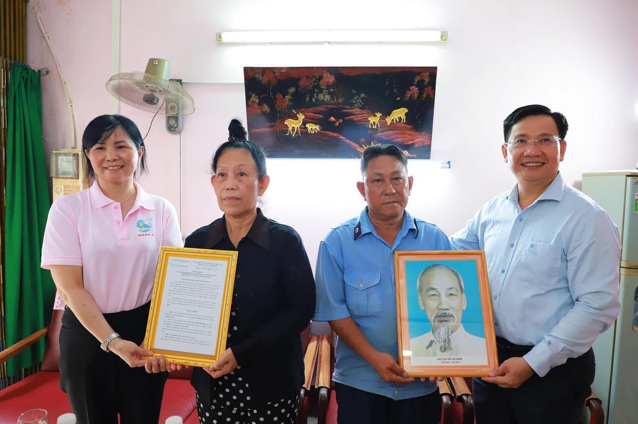 Ông Lý Tấn Hòa - Phó Bí thư quận ủy quận 4 (bìa phải) và bà Đỗ Thị Hương (bìa trái) tặng ảnh Bác Hồ và trao quuyết định tặng mái ấm tình thương cho gia đình bà Phạm Thị Tư