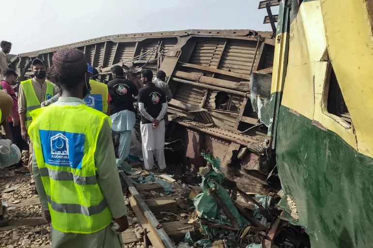 Các tình nguyện viên tìm kiếm các nạn nhân trong các toa sau vụ trật bánh của một chuyến tàu chở khách ở Nawabshah. [AFP]