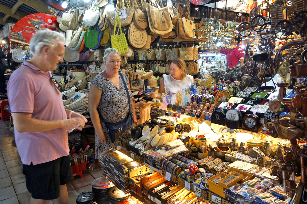 2 du khách nước ngoài đang tham quan sạp hàng bán đồ mỹ nghệ ở chợ Bến Thành.  Từ sau đại dịch COVID-19 lượng khách đến chợ Bến Thành mua hàng sụt giảm rõ rệt - ẢNH: PHÙNG HUY