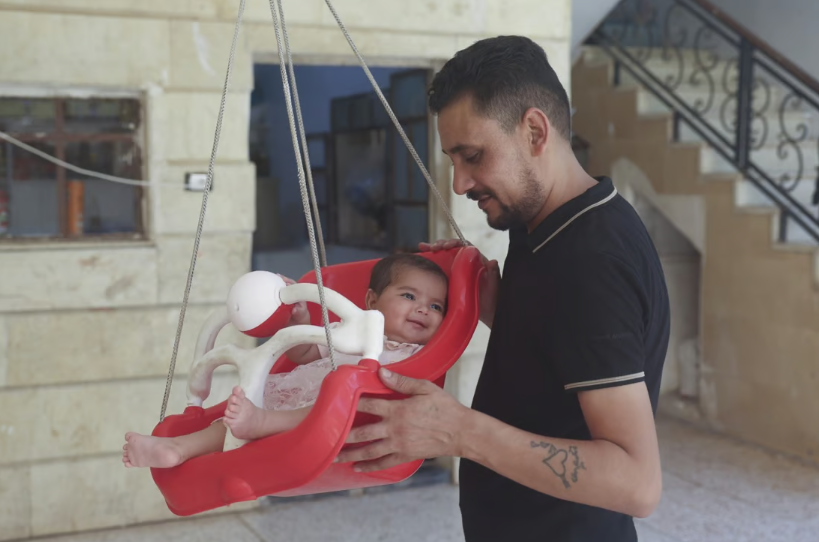 Anh Khalil al-Sawadi chơi với con gái nuôi Afraa ở Jinderis, Syria - Ảnh: AP