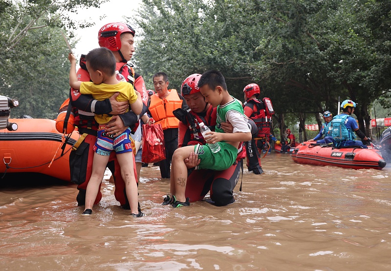 Nhân viên cứu hộ đưa trẻ em ra khỏi vùng lũ lụt ở Trác Châu, thành phố Bảo Định, tỉnh Hà Bắc, Trung Quốc - Ảnh: CFP