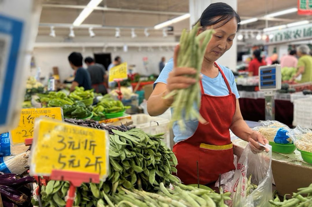 Người bán rau phục vụ khách hàng tại một ngôi chợ ở Bắc Kinh, Trung Quốc ngày 10/8/2023 - Ảnh: REUTERS/Yew Lun Tian