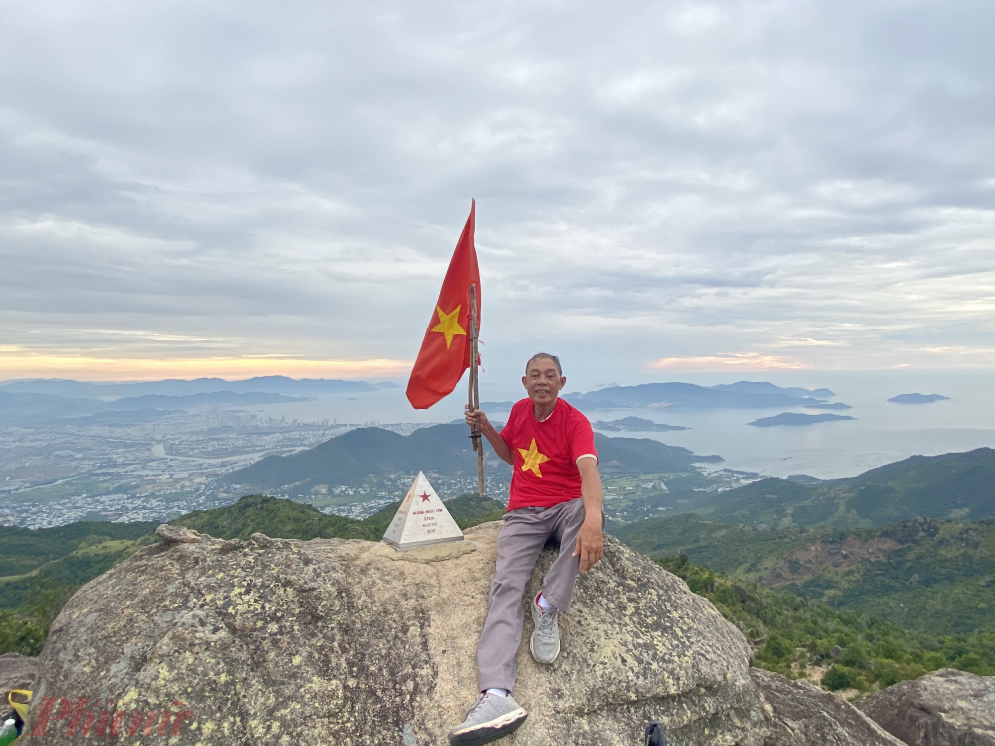 Ông Trần Văn Thọ chụp hình lưu niệm với cột mốc đỉnh núi