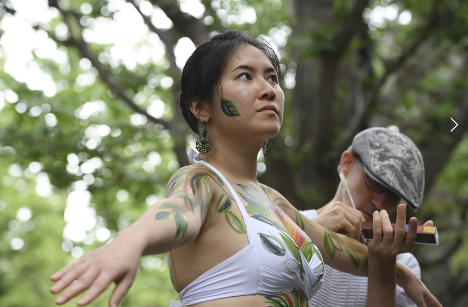 Cô Miho Nakashima đang tạo hình một thân cây với nhiều hình vẽ được sơn lên cơ thể - Ảnh: Stephen Wade /AP