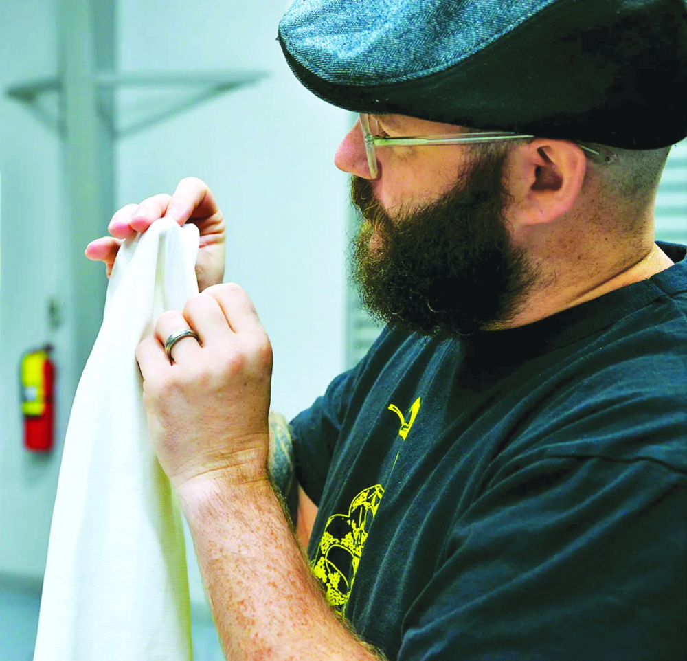 Beckmann kiểm tra chất lượng  một mẫu vải chống muỗi bên trong xưởng dệt kiêm phòng thí nghiệm  tại đại học Auburn  Nguồn ảnh: Specialty Fabrics Review