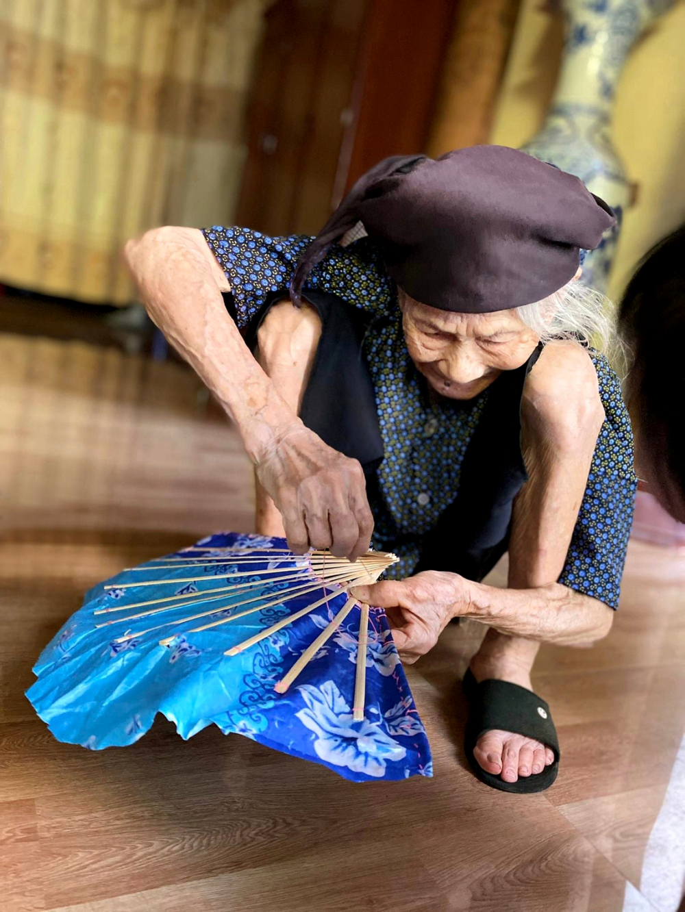 Bà Nghiên năm nay đã 102 tuổi. Bà vẫn khỏe, lúc rảnh vẫn thường ngồi khâu quạt giấy