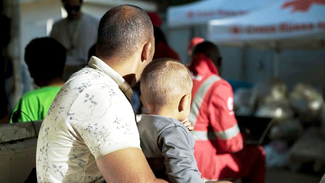 2 bố con người Tunisia di cư ngồi gần lều của Hội Chữ thập đỏ Ý tại trung tâm tiếp nhận trên đảo Lampedusa. Nhiều đứa trẻ khác phải di cư một mình, không may mắn có cha như em bé này - Nguồn ảnh: UNICEF