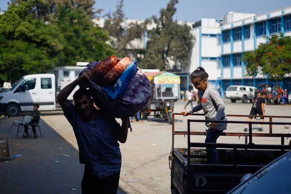 Một người đàn ông Palestine chạy trốn khỏi nhà sau các cuộc tấn công của Israel, mang đồ đạc đến nơi trú ẩn trong một trường học do Liên hợp quốc điều hành, ở thành phố Gaza ngày 8 tháng 10