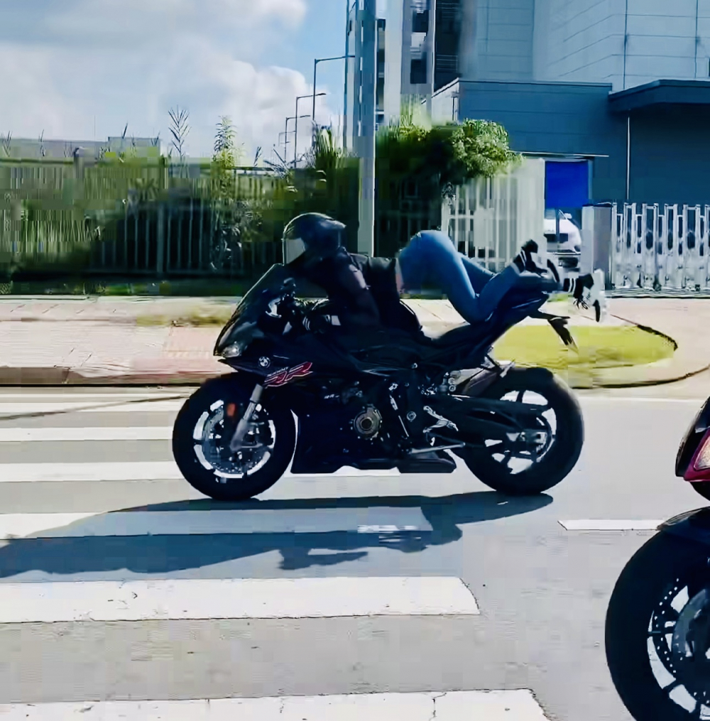 Người mẫu Ngọc Trinh nằm lái xe mô tô phân khối lớn trên đường. 