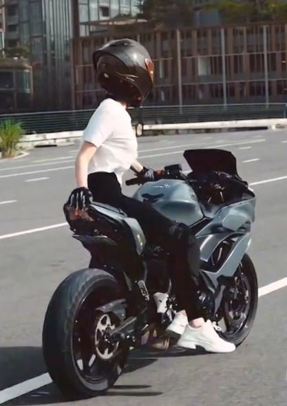 Hình ảnh người mẫu Ngọc Trinh biểu diễn thả 2 tay, ngồi 1 bên khi lái xe mô tô