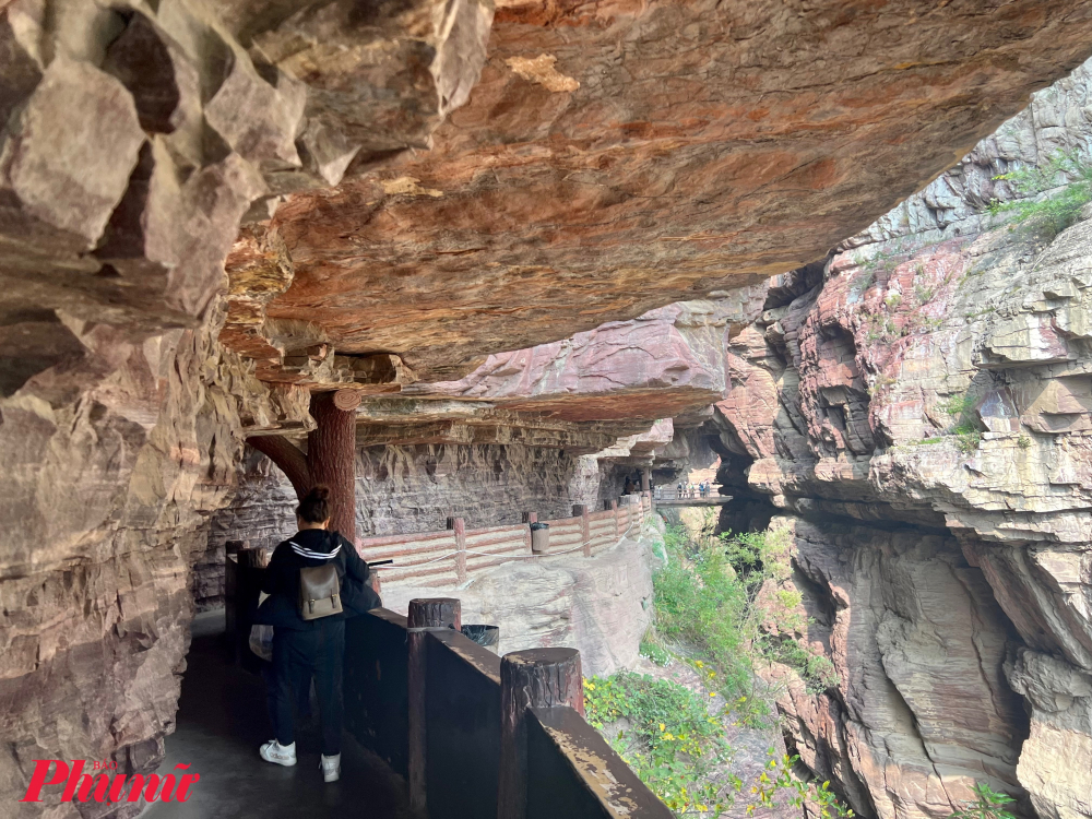 Điểm đầu tiên khách thường lựa chọn tham quan ở khu thắng cảnh Vân Đài Sơn là Hongshi Valley (Red Rock Valley hay Thung lũng hồng thách). Đây là nơi có phong cảnh độc đáo, với các rãnh nước suối đổ từ trên cao xuống. Các vách đá ở đây có màu đỏ đặc trưng, cùng với những rãnh nước suối chảy qua hàng triệu năm trước, tất cả tạo nên một khung cảnh ấn tượng. Trong ảnh: Du khách sẽ trải nghiệm đi bộ ở con đường men theo các vạch núi hồng, ngắm nhìn những vách núi sừng sững điểm tô thảm thực vật độc đáo như mọc ra từ đá rất đẹp mắt.