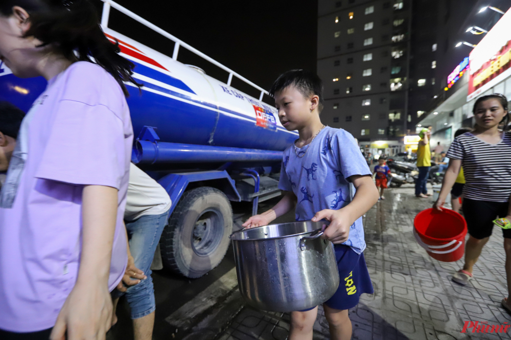 Các em nhỏ mang theo chai nhỏ, nồi lớn phụ giúp gia đình chờ lấy nước.