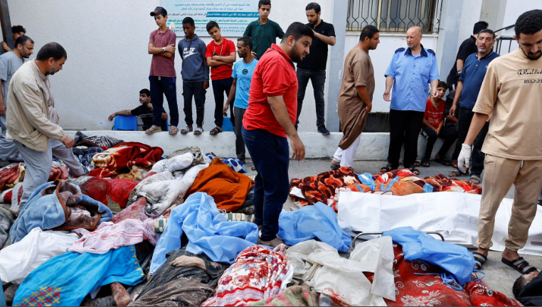 Người dân tụ tập quanh thi thể của những người Palestine thiệt mạng trong cuộc không kích của Israel vào Bệnh viện Ả Rập al-Ahli ở trung tâm Gaza sau khi họ được chuyển đến Bệnh viện Shifa. [Dawood Nemer/AFP]