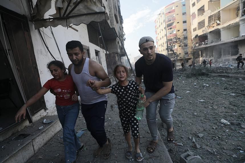Hai người đàn ông giúp hai cô gái trẻ bị thương rời khỏi khu vực sau cuộc không kích của Israel ở Gaza. 