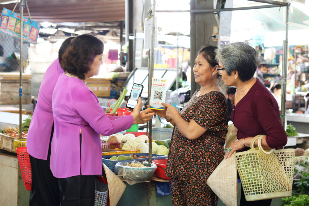 Tiểu thương Huỳnh Thị Thu, chợ Ngã Ba Bầu (thứ 2, từ phải qua) chia sẻ với chị em nội trợ về cách thức thanh toán không dùng tiền mặt - ẢNH: MẪN NH