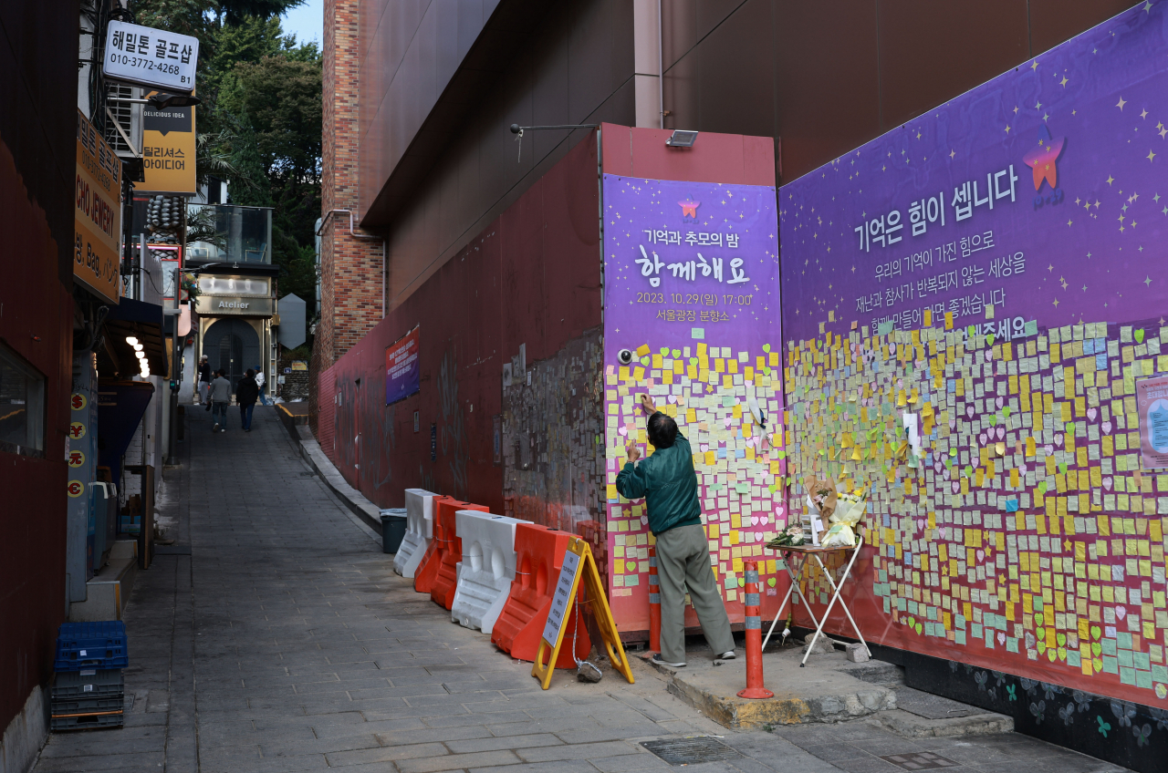 Một người đàn ông dán những lời thương tiếc cho các nạn nhân của vụ đám đông đè bẹp ở Itaewon, Seoul, trước lễ tưởng niệm 1 năm thảm kịch. (Ảnh: Yonhap)