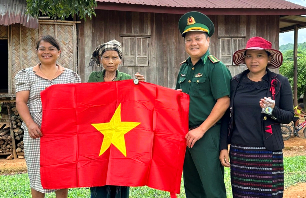 Chị Hồ Thị Thiệt (ngoài cùng bên trái) tặng cờ Tổ quốc cho người dân thôn Sê Pu - Tà Păng - ẢNH: THUẬN HÓA