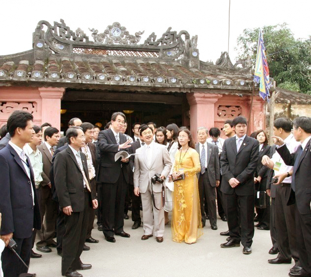 Tác giả (áo dài vàng) đưa hoàng thái tử Nhật Naruhito đến trước Chùa Cầu vào năm 2009