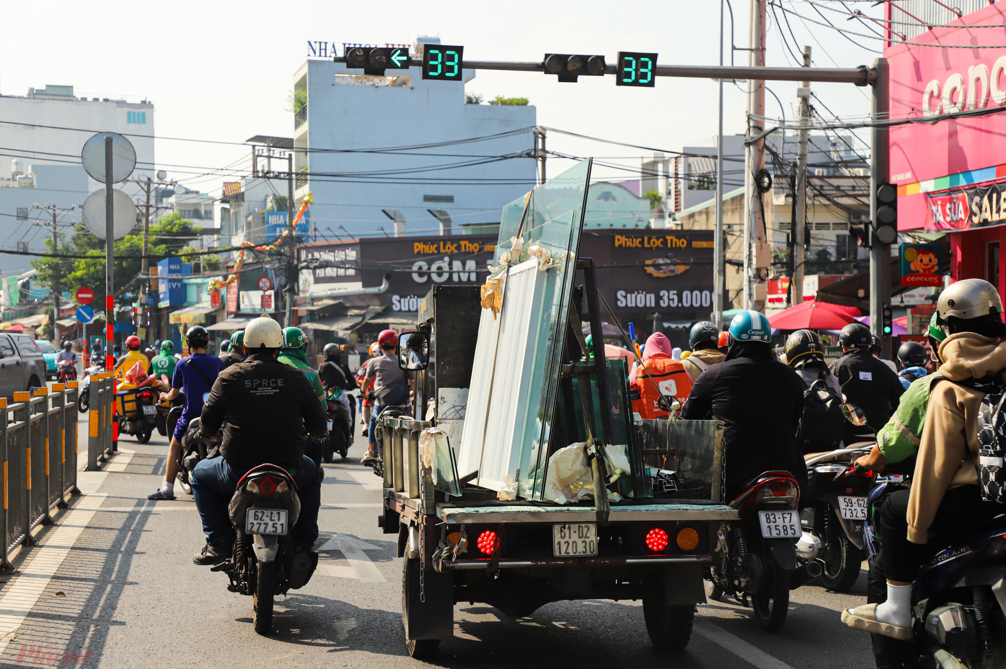Chiếc xe ba gác chở kính chen chúc với dòng người đi xe máy trên đường Nguyễn Xí, quận Bình Thạnh.