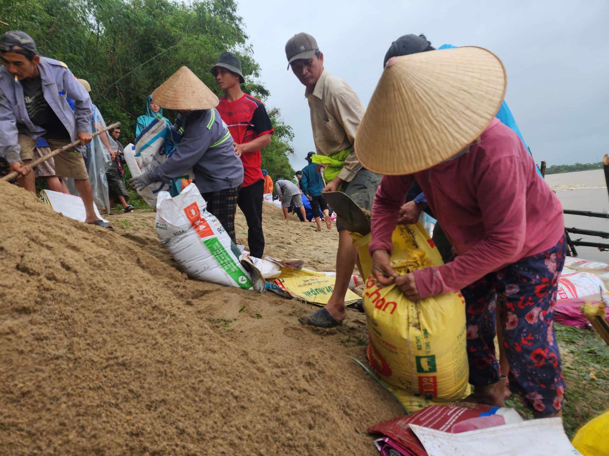 cả những người phụ nữ cũng tham gia để làm bờ kè chống sạt lở, uy hiếp ngôi nhà của mình