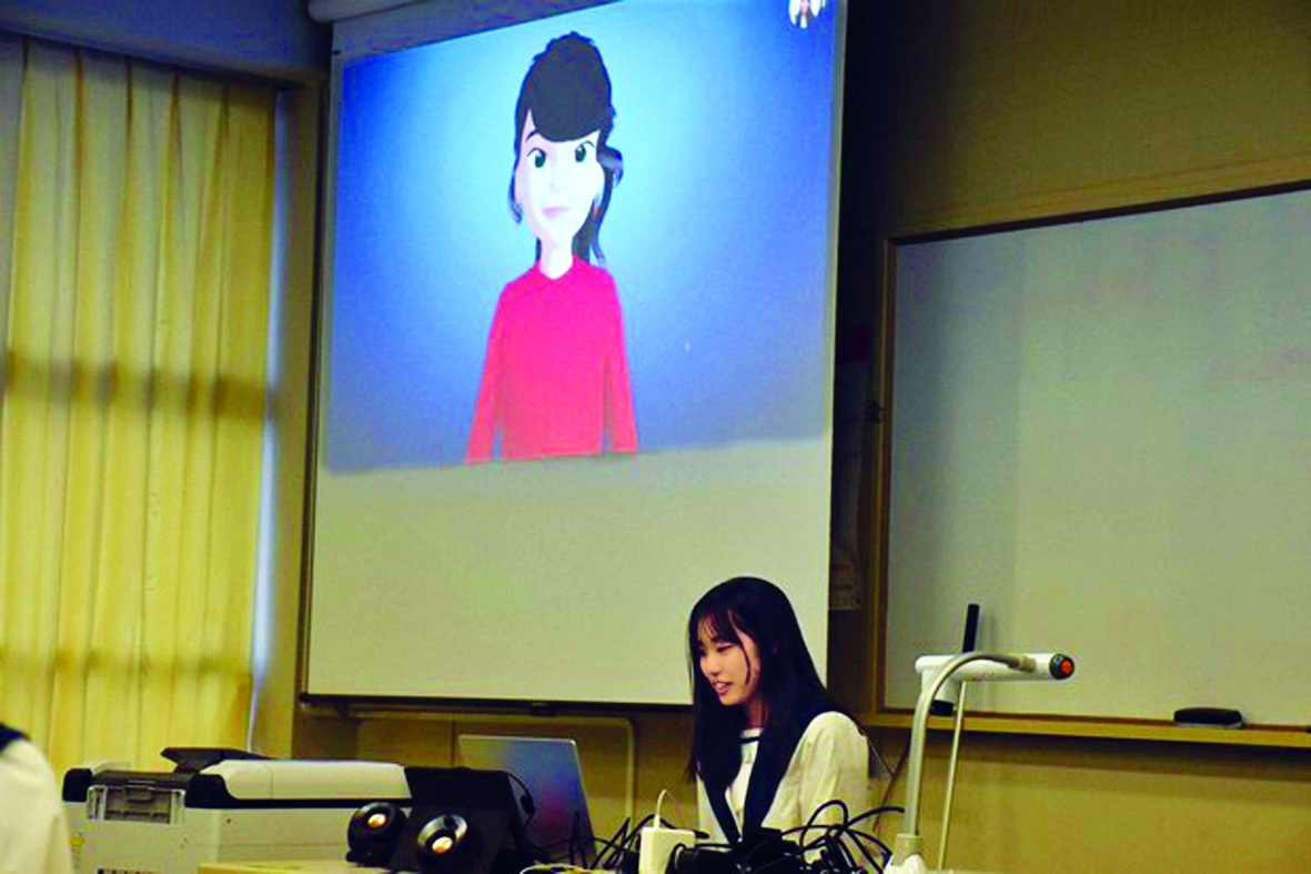 Một học sinh sử dụng máy tính để giao tiếp bằng tiếng Anh với nhân vật AI nhìn thấy trên màn hình phía trên bên trái, tại Trường trung học Narita Kokusai ở TP Narita, tỉnh Chiba, Nhật Bản - ẢNH: TATSUYA NAGANUMA