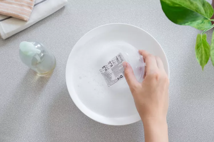 Nhúng nhựa vào nước xà phòng Nếu có thể, hãy ngâm vật bằng nhựa vào nước xà phòng và để yên trong 15 phút cho đến khi nhãn dán mềm ra và phần cặn bắt đầu bong ra.