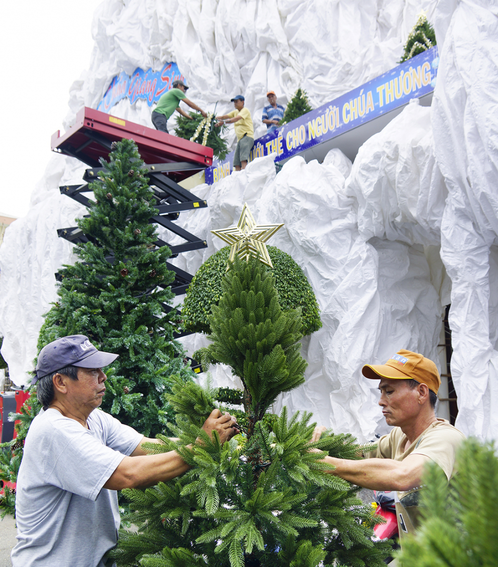 Giáo dân chăm chút trang trí các cây thông để chuẩn bị đưa lên núi đá trên cao.