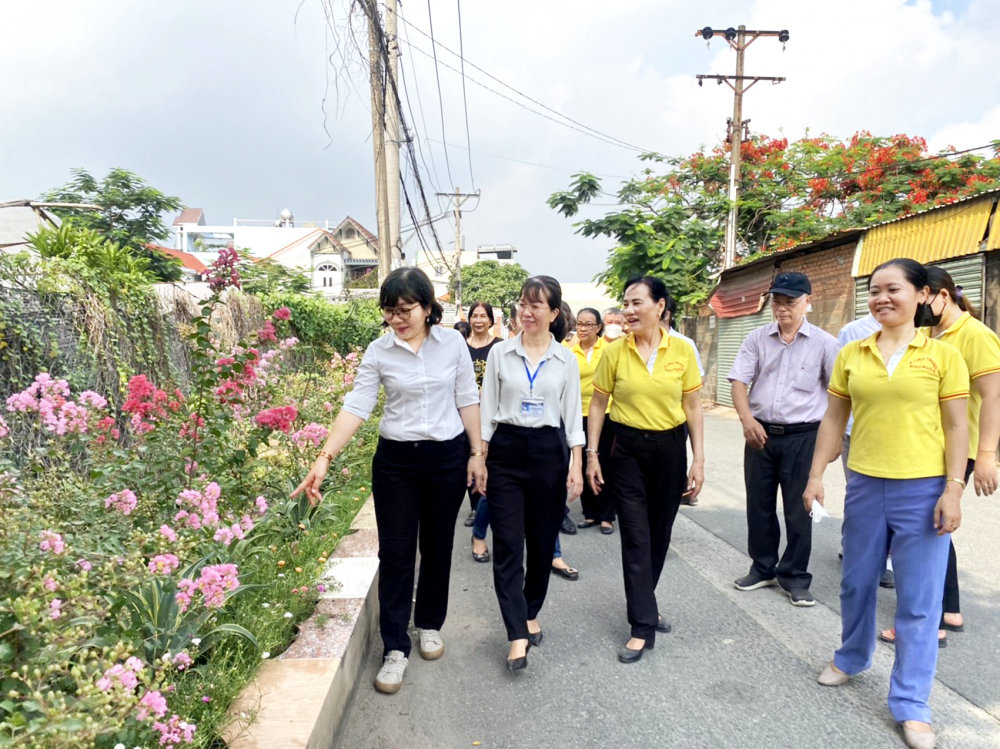 Bà Nhàn (thứ ba từ trái sang) giới thiệu với lãnh đạo địa phương những bồn hoa, chậu cây trong hẻm 1078 Quốc lộ 1 sau khi hoàn thành  cải tạo 