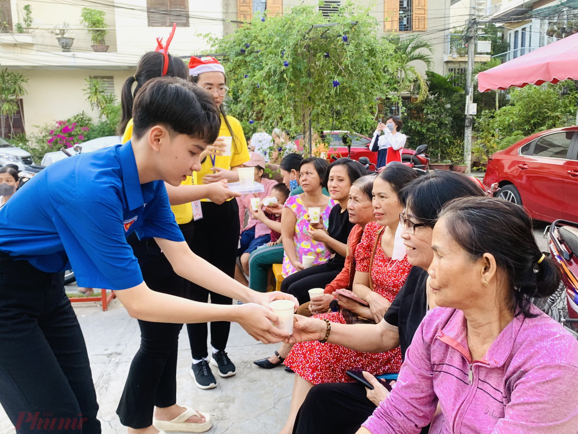 Các tình nguyện viên phục vụ sữa bí đỏ miễn phí cho phụ huynh và người dân địa phương