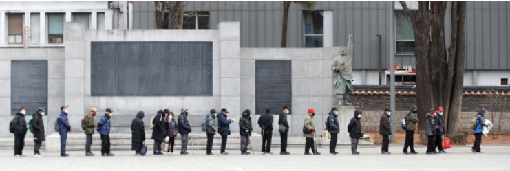 Mọi người xếp hàng chờ đợi tại Công viên Tapgol ở trung tâm Seoul để nhận hộp cơm trưa như một phần của chương trình bữa ăn miễn phí của thành phố. (The Korea Herald DB)