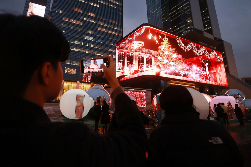 Mọi người thưởng thức '”Buổi biểu diễn truyền thông Giáng sinh” trước bảng điện tử lớn tại COEX K-Pop Square ở Gangnam, Seoul, như một phần của Tuần lễ nghệ thuật truyền thông Seoul 2023