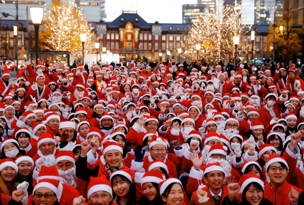 Những người tham gia mặc trang phục ông già Noel tạo dáng chụp ảnh trước sự kiện phát quà và dọn dẹp đường phố ở Tokyo, Nhật Bản