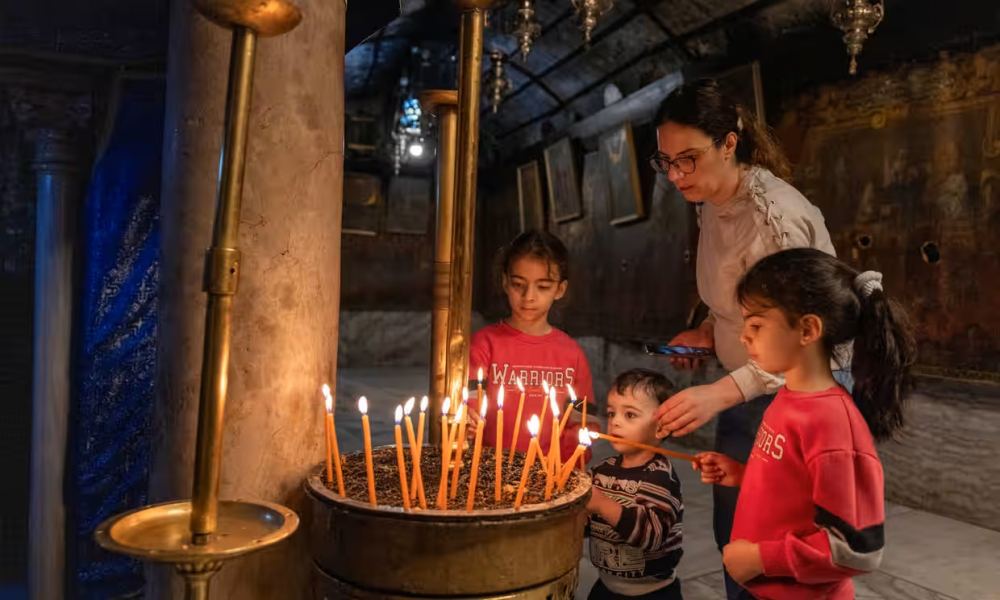 Trẻ em thắp nến trong Nhà thờ Giáng sinh hoang vắng ở thị trấn Bethlehem, quê hương của Chúa Jesus