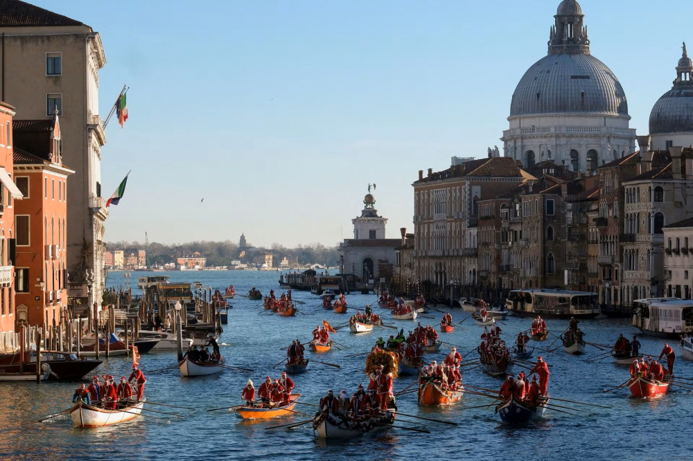 Mọi người hóa trang thành ông già Noel chèo thuyền trong cuộc đua thuyền Giáng sinh dọc theo Grand Canal ở Venice, Ý