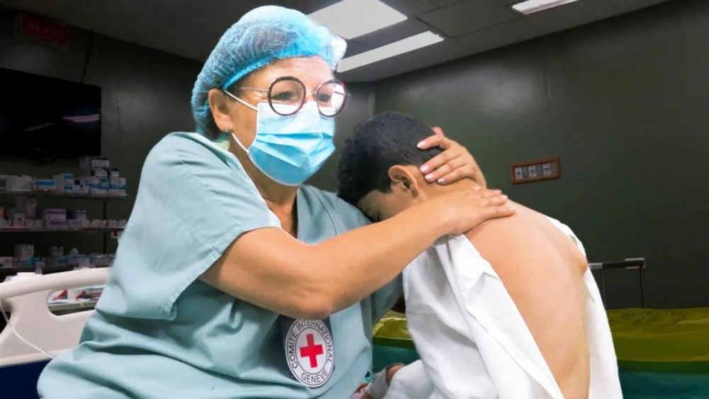 Một bác sĩ của Ủy ban Chữ thập đỏ quốc tế (ICRC) an ủi một cậu bé bị thương ở Gaza - Nguồn ảnh: ICRC