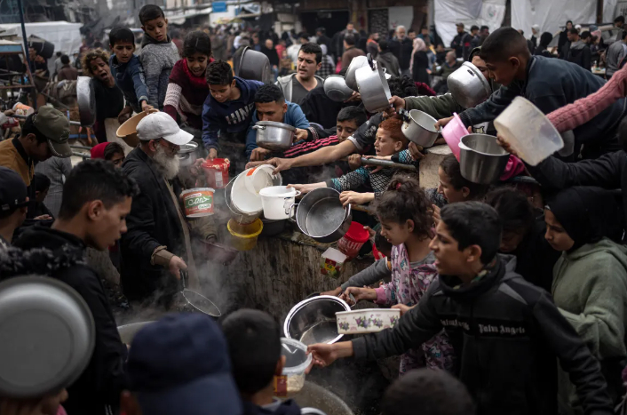 Người Palestine xếp hàng để nhận bữa ăn miễn phí ở Rafah vào ngày 21/12/2023. Các cơ sở viện trợ quốc tế cho biết Gaza đang rơi vào tình trạng thiếu lương thực, thuốc men và các nhu yếu phẩm cơ bản khác. [Ảnh Fatima Shbair/AP]