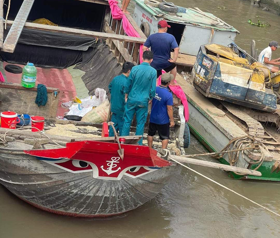 Lực lượng chức năng cùng người dân hỗ trợ đưa người, máy móc cùng số gạo bị chìm lên bờ