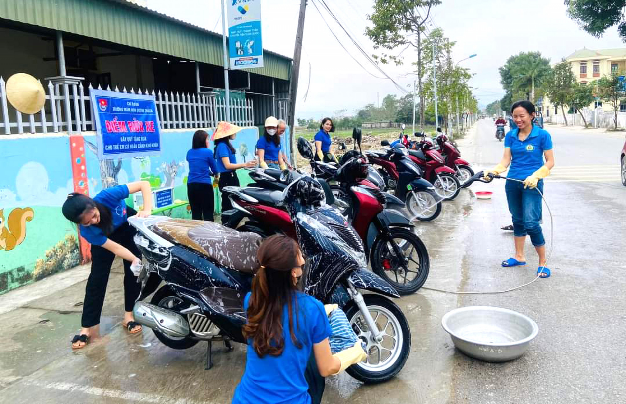 Hành lang trước cổng Trường mầm non Quỳnh Thạch trở thành điểm rửa xe gây quỹ của các cô - Ảnh: Nguyễn Hành