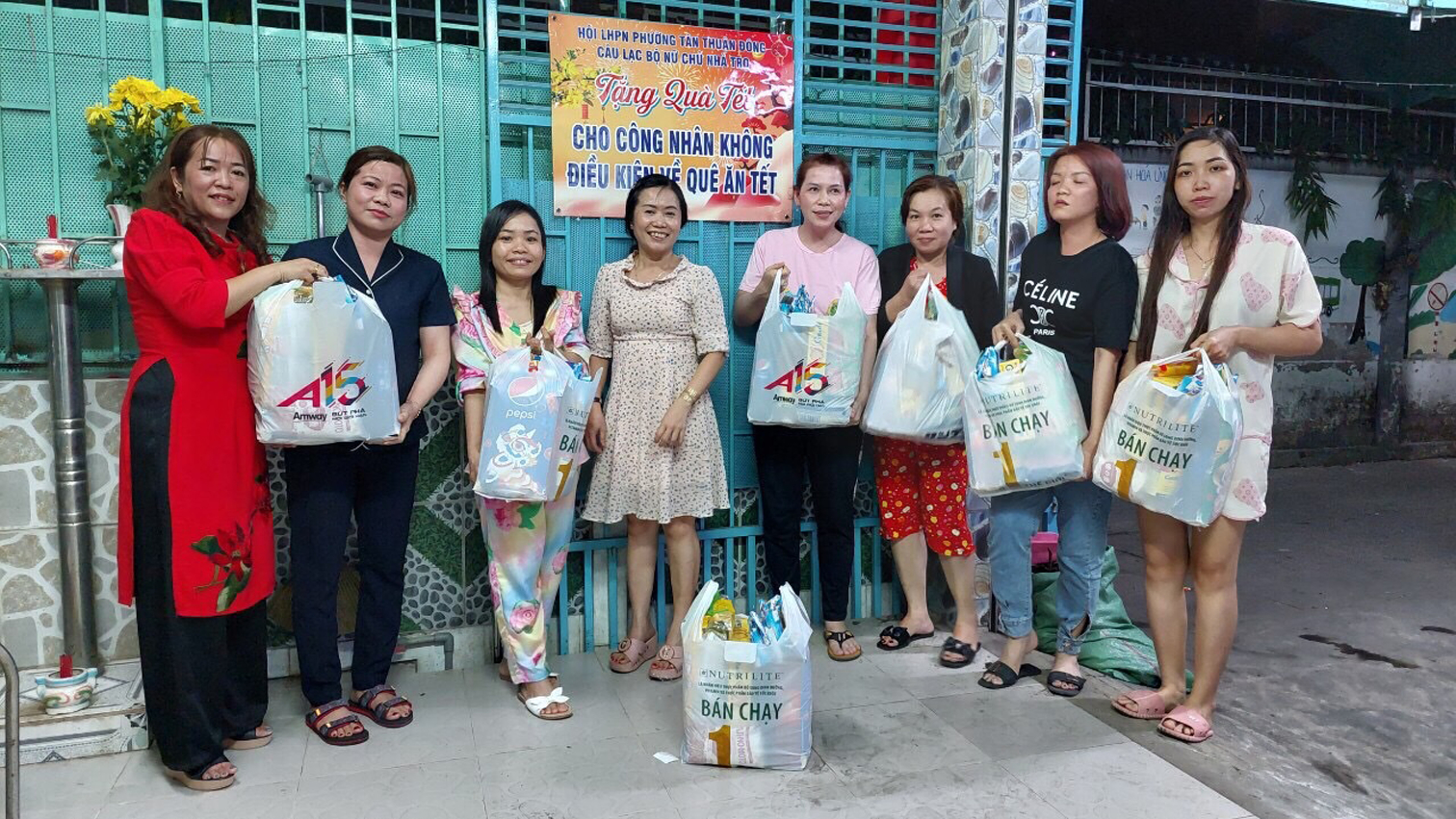 Bà Đặng Thị Ngọc Hải (thứ tư từ trái sang) - nữ chủ nhà trọ phường Tân Thuận Đông - trao quà cho nữ công nhân lao động không có điều kiện về quê đón tết