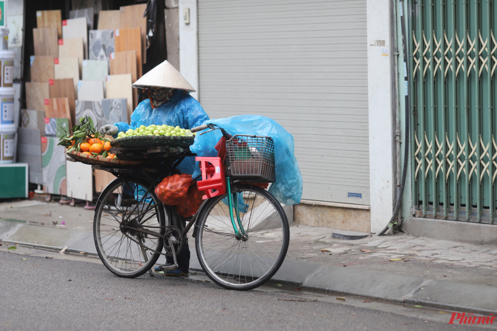 Người lao động bán hàng rong phải mặc thêm các lớp áo mưa mỏng bên ngoài để cản gió.