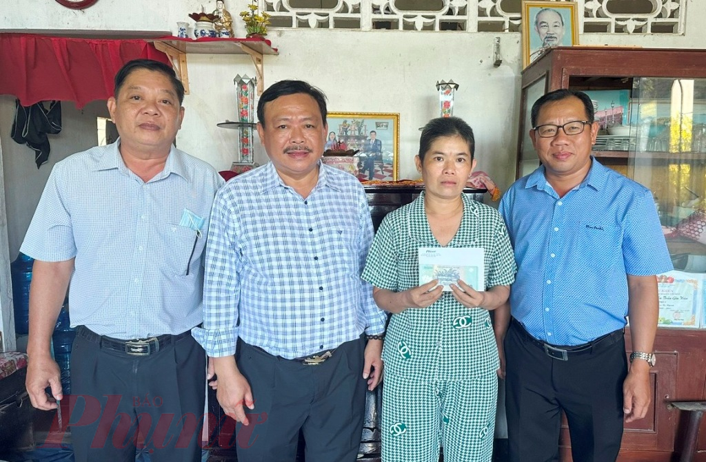 Nhà báo Huỳnh Lợi - Trưởng văn phòng đại diện Báo Phụ nữ TPHCM tại ĐBSCL (bìa phải) - cùng chính quyền địa phương trao tiền hỗ trợ cho chị Nhân