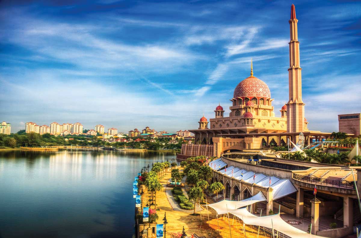 Putrajaya, thủ đô hành chính của Malaysia, là điểm đến mới mẻ và độc đáo, chắc chắn sẽ gây ấn tượng mạnh mẽ với du khách. Cách thành phố sôi động Kuala Lumpur 25 km, Putrajaya tự hào với kiến trúc thành phố vườn, với công trình nhà cửa chỉ chiếm 25% diện tích, còn lại là không gian xanh của công viên, khu thể thao và vườn thiên nhiên.  Thành phố này thể hiện tham vọng lớn lao của Malaysia khi xây dựng một kỳ quan văn hóa nghệ thuật, do chính người Malaysia thiết kế. Điểm độc đáo là sự kết hợp của giá trị truyền thống hiện hữu trong từng ngõ ngách của Putrajaya. Những ngọn đèn đường được thiết kế cách điệu như những bó đuốc vĩnh cửu, làm sáng bừng toàn bộ thành phố, tạo nên không khí phá cách và độc đáo.  Đến với Putrajaya, du khách không thể bỏ qua đền thờ Hồi giáo Masjid Putra - một công trình tôn giáo đẹp như tranh với mái vòm màu hồng lung linh bên hồ trong veo, tạo nên khung cảnh tuyệt vời và kỳ ảo. Những cây cầu qua hồ Putrajaya, đặc biệt là cây cầu Putra - cầu hai tầng đầu tiên của Malaysia, cầu Seri Gemilang được trang trí bằng vàng và đá cẩm thạch, đều là điểm cuốn hút không thể bỏ qua.  Trung tâm hội nghị Putrajaya, đặt trên một quả đồi, mang đến tầm nhìn bao quát toàn bộ thành phố. Vở nhạc kịch Rain Forrest tại đây là một trải nghiệm không thể bỏ qua, kết hợp âm nhạc, nội dung hấp dẫn và màn trình diễn đầy thách thức, thể hiện quan điểm yêu thiên nhiên và lòng yêu thương của người dân Malaysia. Putrajaya, nơi hội tụ giữa nghệ thuật và văn hóa, chắc chắn sẽ là điểm đến thú vị trong hành trình của bạn.