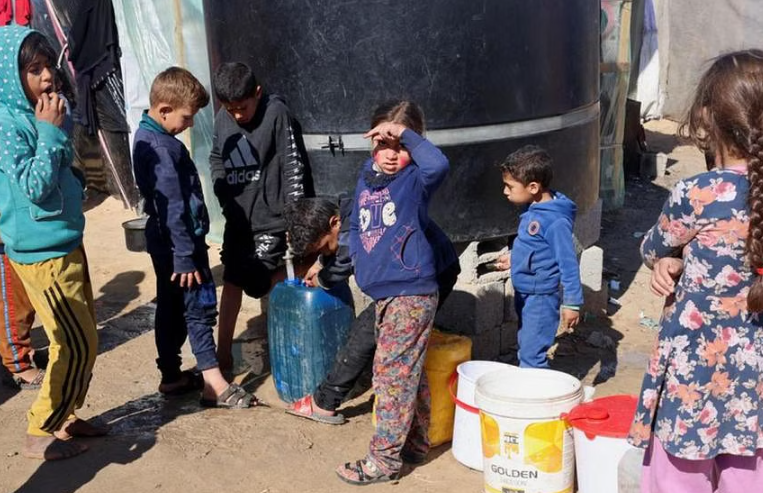 Những đứa trẻ Palestine tại một trại lều ở Rafah, phía nam Dải Gaza ngày 1/2phải di dời, phải rời bỏ nhà cửa do các cuộc tấn công của Israel đang chờ lấy nước trong bối cảnh thiếu nước, 