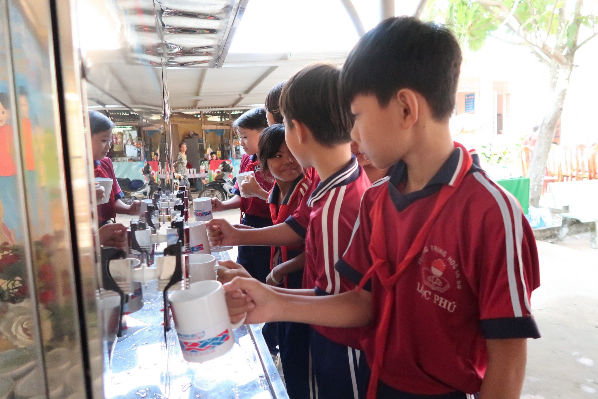 Các em học sinh trường Tiểu học và THCS Lộc Phú thích thú với những giọt nước mát lành từ hệ thống máy lọc nước vừa được trang bị cho trường học