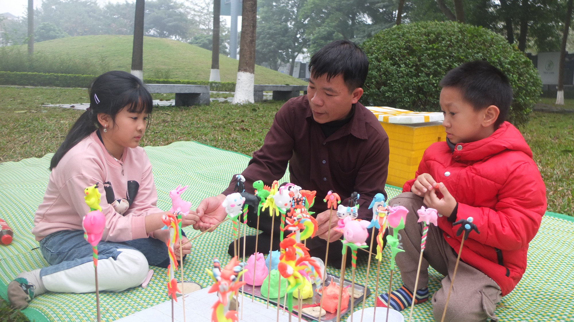Nghệ nhân làng Xuân La hướng dẫn các em nhỏ cách vê bột, tạo hình.